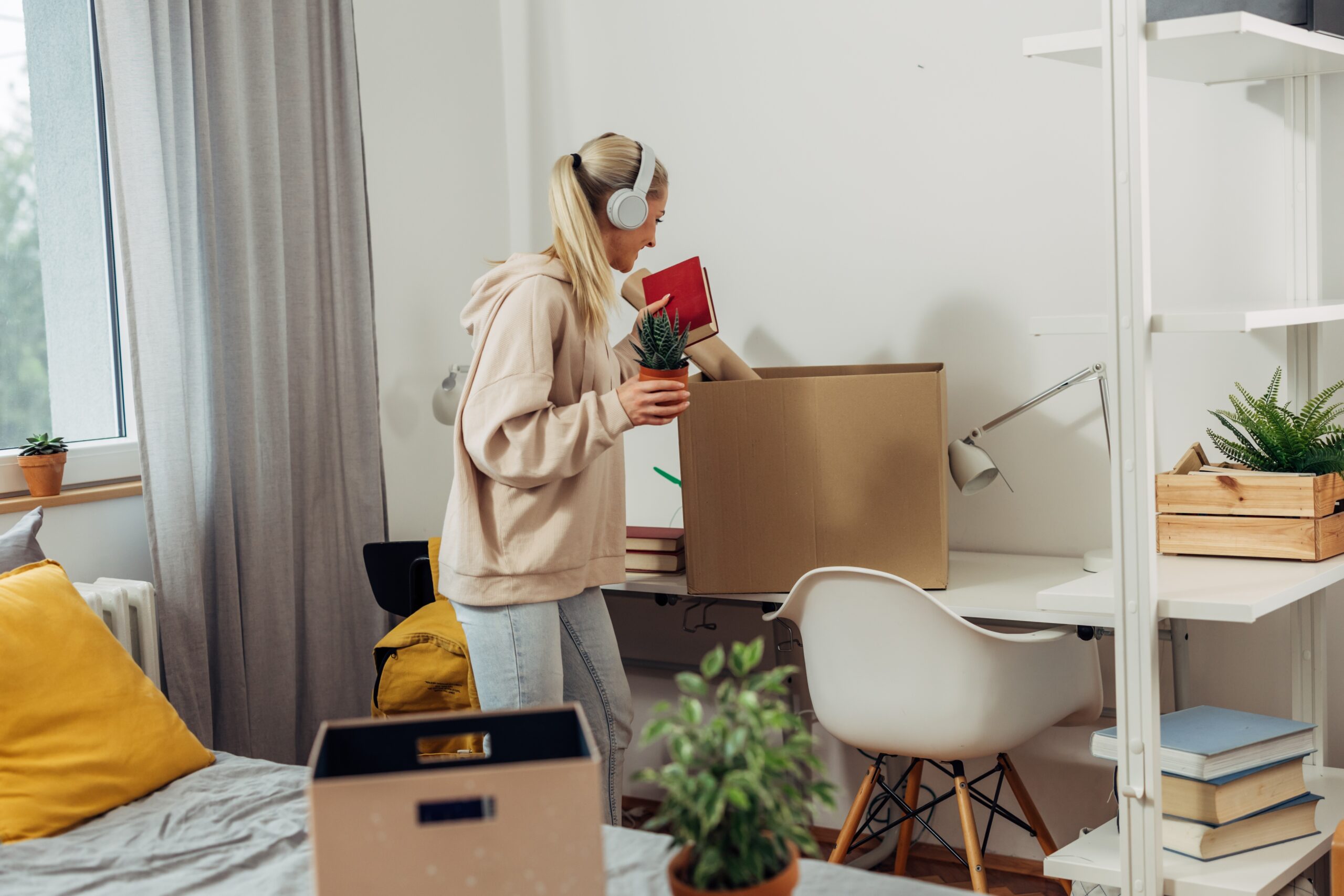 Female student packing dorm room items in boxes for moving