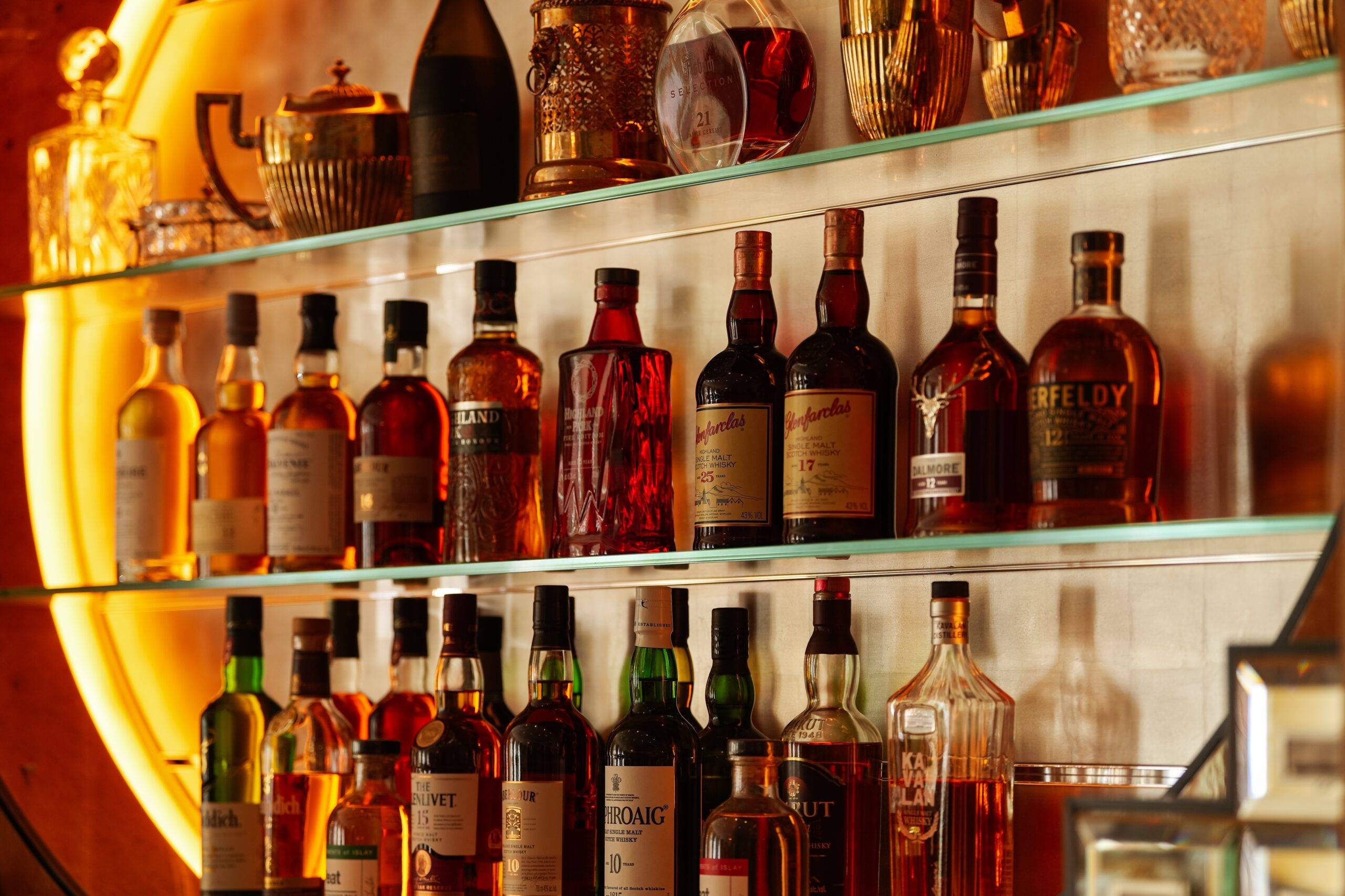 Bottles of whiskey and other alcohol displayed on shelves at a bar